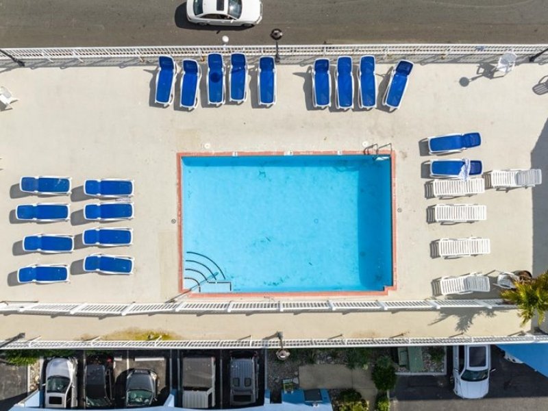 an overhead view of a pool with blue chairs