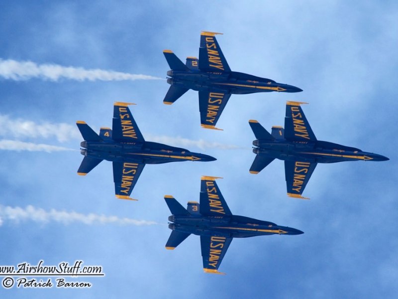 four blue angels jets flying in formation with smoke coming from them