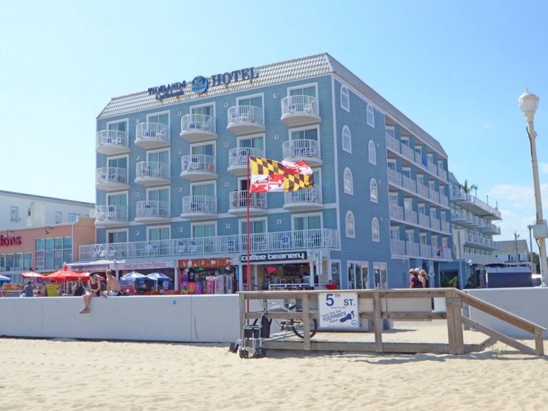 a hotel on the beach with people walking around