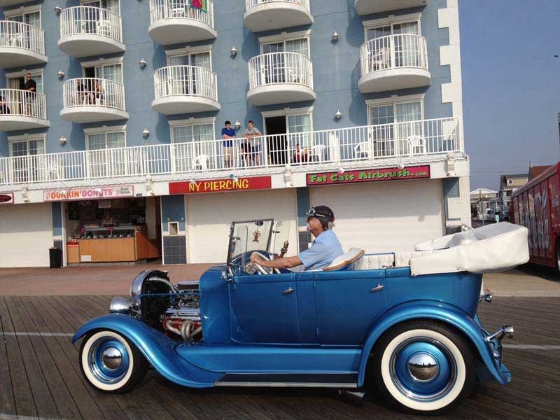 a man driving an old fashioned car in front of a hotel