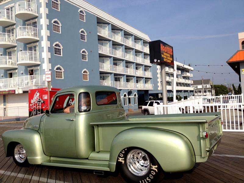 an old green truck parked in front of a hotel